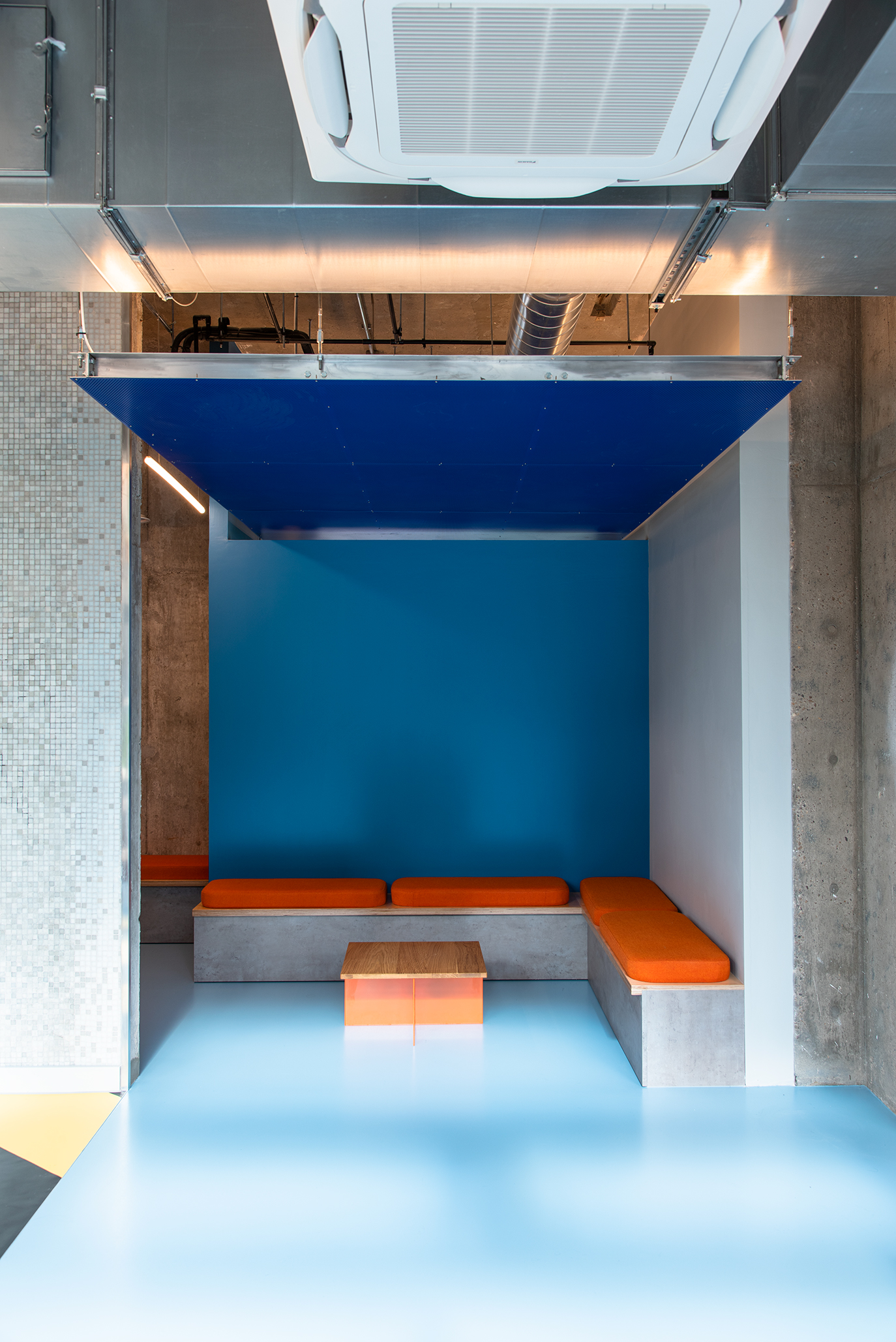 Blue resin floor for student accommodation, with corner sofa and dark blue ceiling