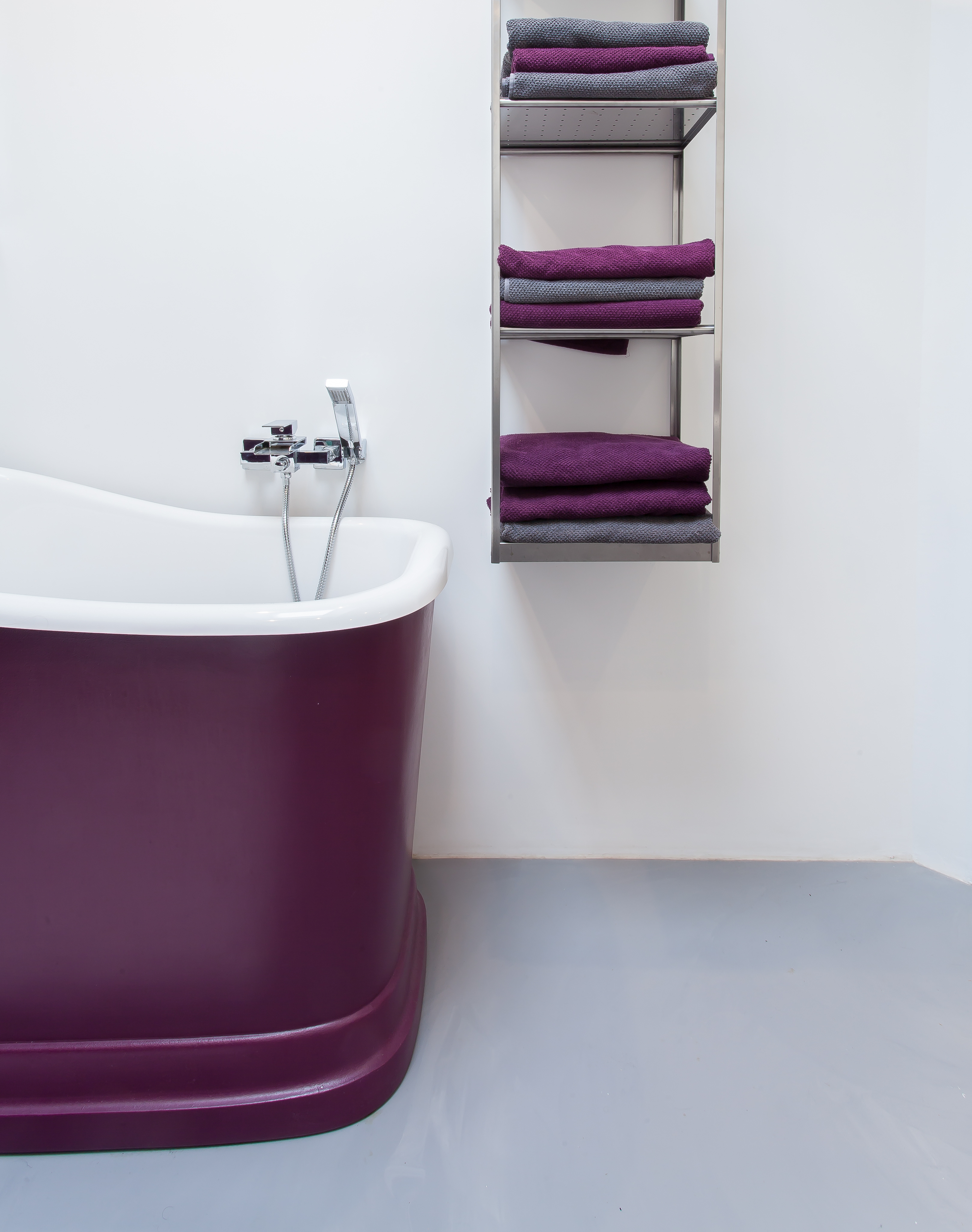 Grey resin bathroom floor, with purple and white bath