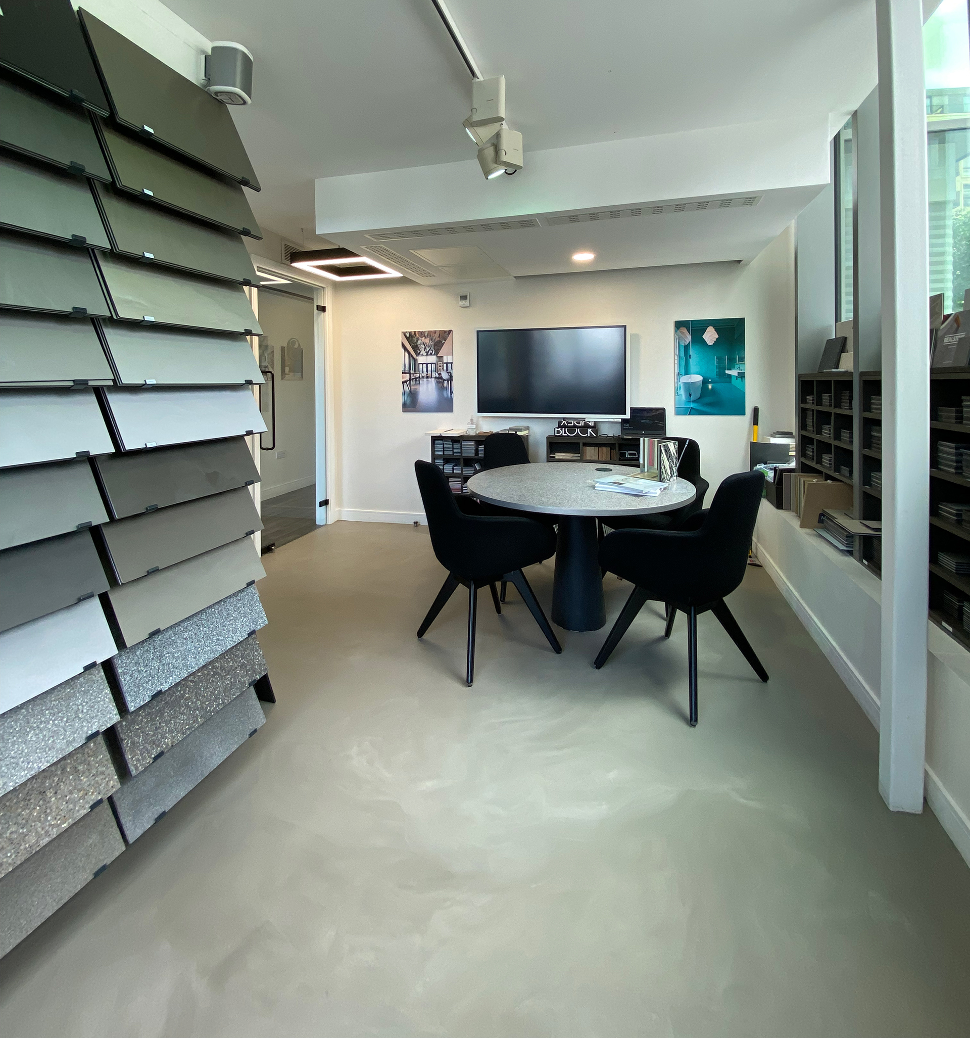 Wandsworth showroom with light grey resin floor, racks of resin floor samples, and a table and chairs