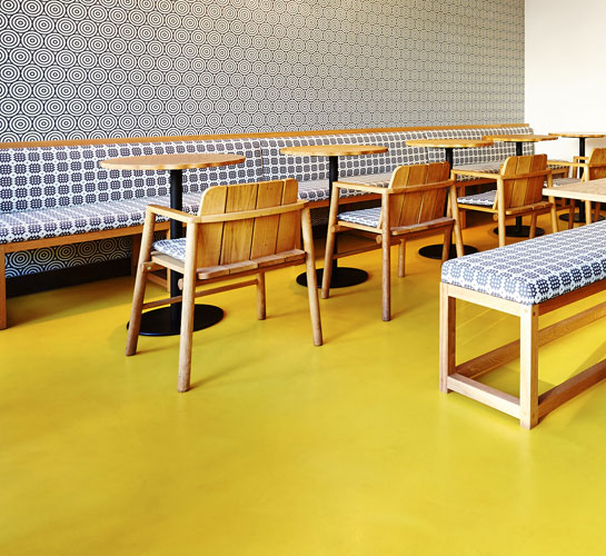 Yellow resin restaurant flooring with wooden and patterned table and chairs