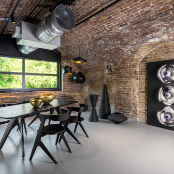 Light grey commercial resin flooring with a dining table and chairs, and an exposed brick wall