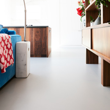 Light grey resin alternative to polished concrete floor in a bedroom