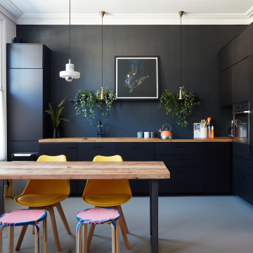 Dark grey resin kitchen floor with table and chairs, and black wall