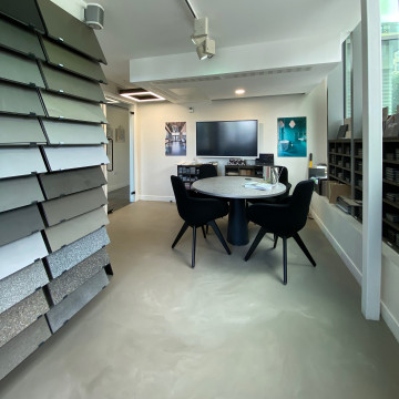 Wandsworth showroom with light grey resin floor, racks of resin floor samples, and a table and chairs