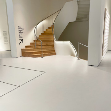 Light grey resin museum floor with wood staircase