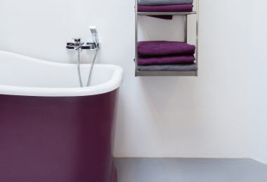 Grey resin bathroom floor, with purple and white bath