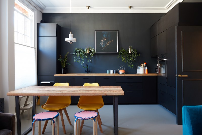 Dark grey resin kitchen floor with table and chairs, and black wall