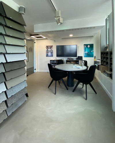 Wandsworth showroom with light grey resin floor, racks of resin floor samples, and a table and chairs