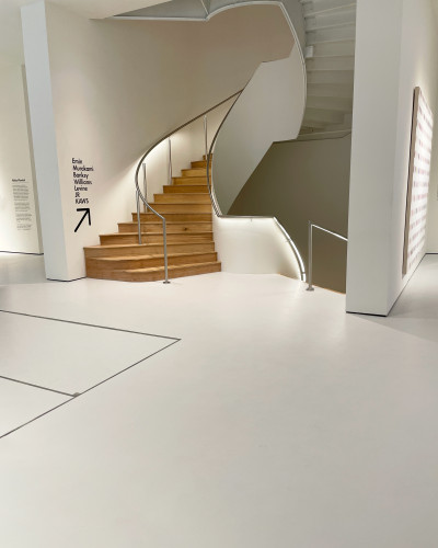 Light grey resin museum floor with wood staircase